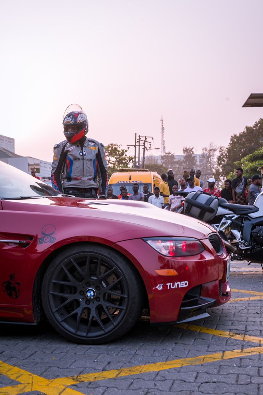 A rider beside a red BMW at sunset